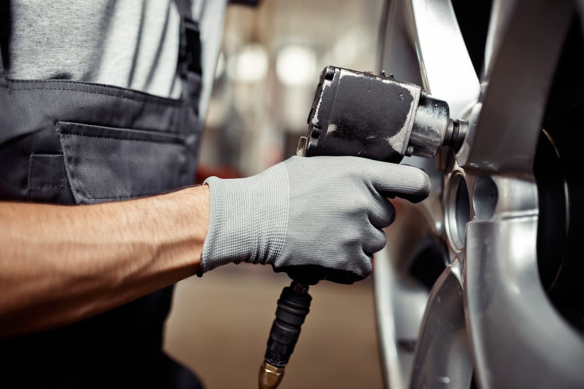 Homme revissant une roue de voiture