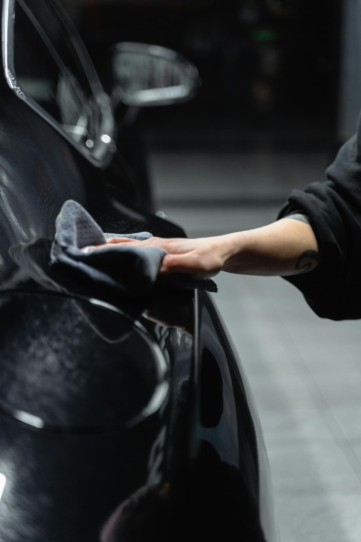 Personne nettoyant une voiture noire avec un chiffon