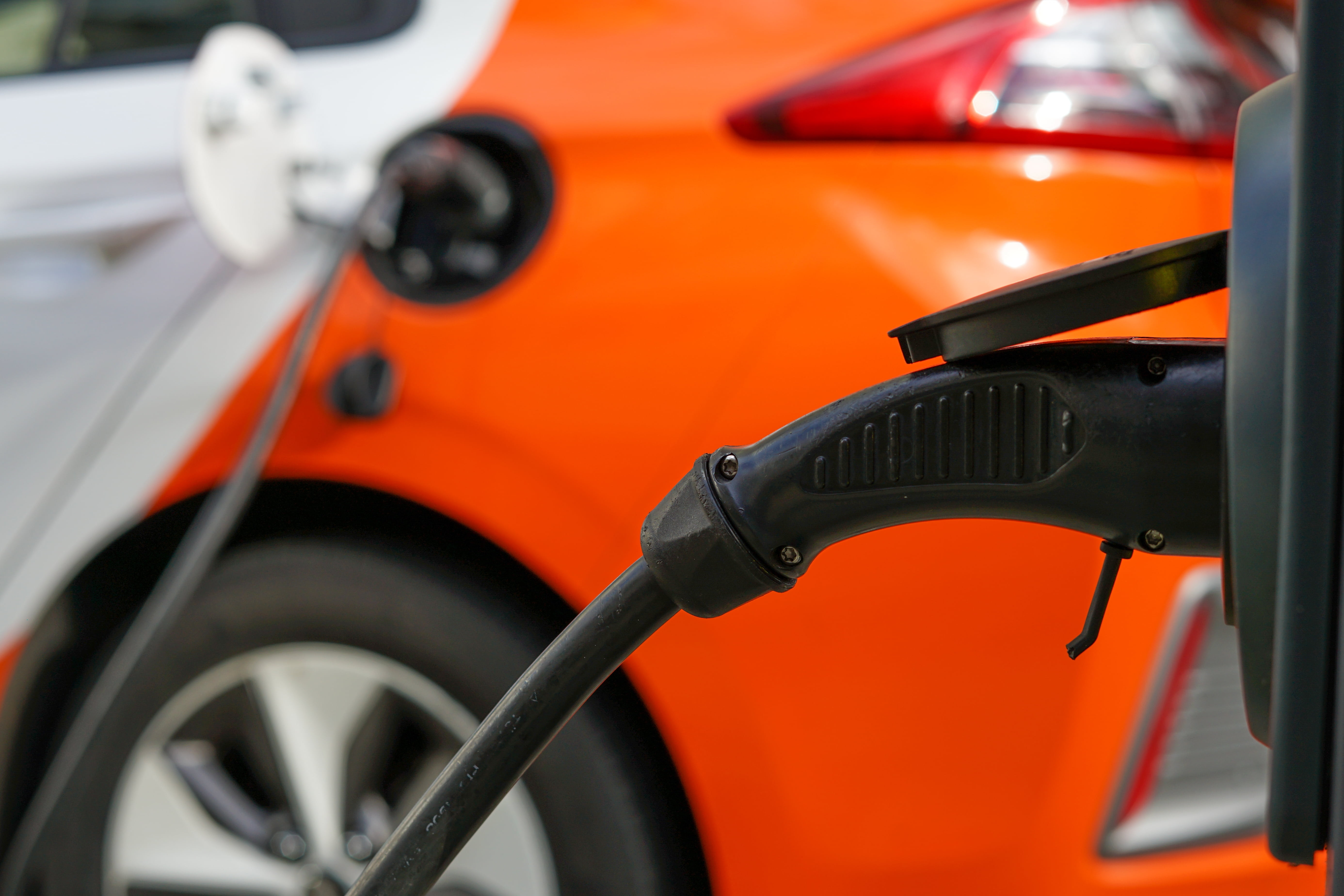 Voiture électrique orange en cours de recharge sur une borne