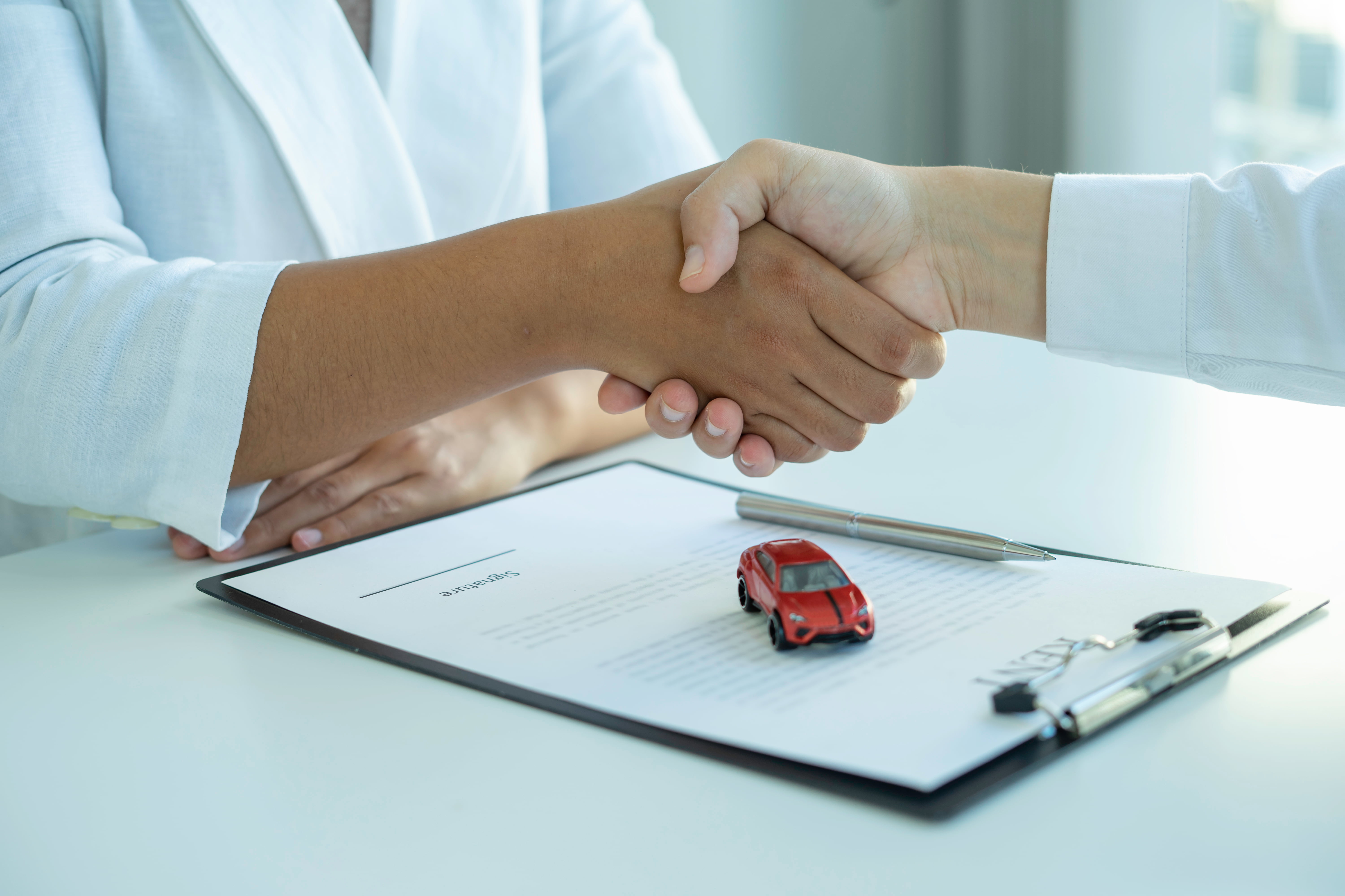 Poignee de main entre un acheteur et un vendeur de voiture avec un contrat