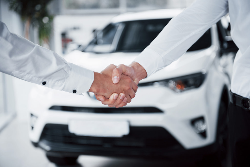 gros-plan-du-directeur-des-ventes-en-costume-noir-vendant-la-voiture-au-client