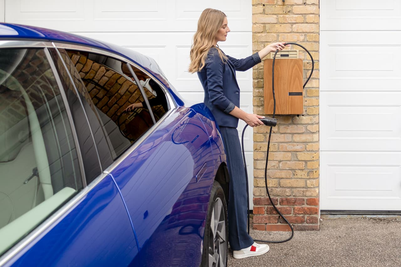 Femme rechargeant une voiture électrique d'occasion à domicile avec une borne murale