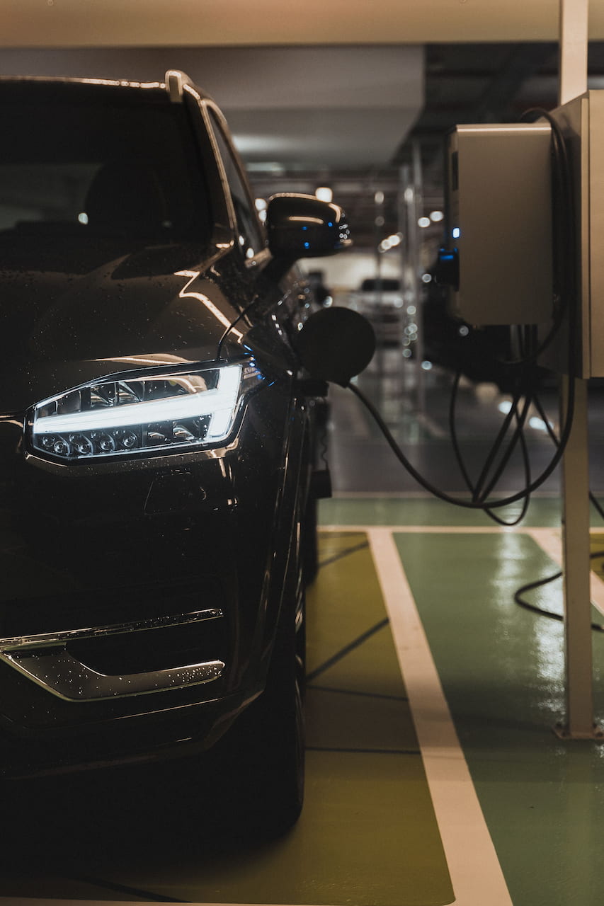 SUV électrique d'occasion branché sur une borne de recharge en parking couvert
